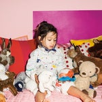 Little girl on her bed surrounded by stuffed animals