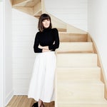 Woman standing by staircase wearing white pants and a black turtleneck