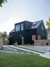 All-black steel house exterior with green grass lawn.