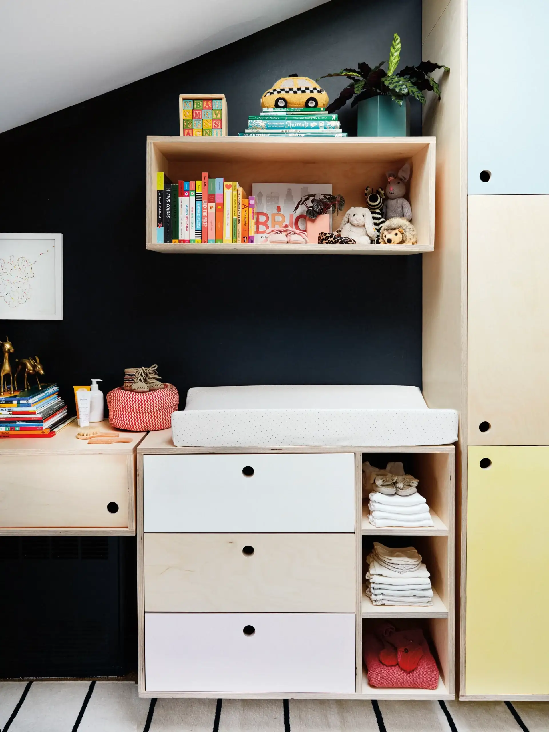 Nursery with colorblocked drawers and black wall.
