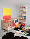 Nursery with colorblock art and throw blanket, plus cowhide rug.