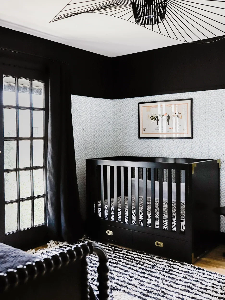 Nursery with black crib, pendant light, and trim.