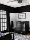 Nursery with black crib, pendant light, and trim.