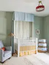 Nursery with pastel blue and green walls, gingham glider, and red ceiling light. 