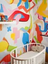 Nursery with colorful hand-painted mural and oval crib.