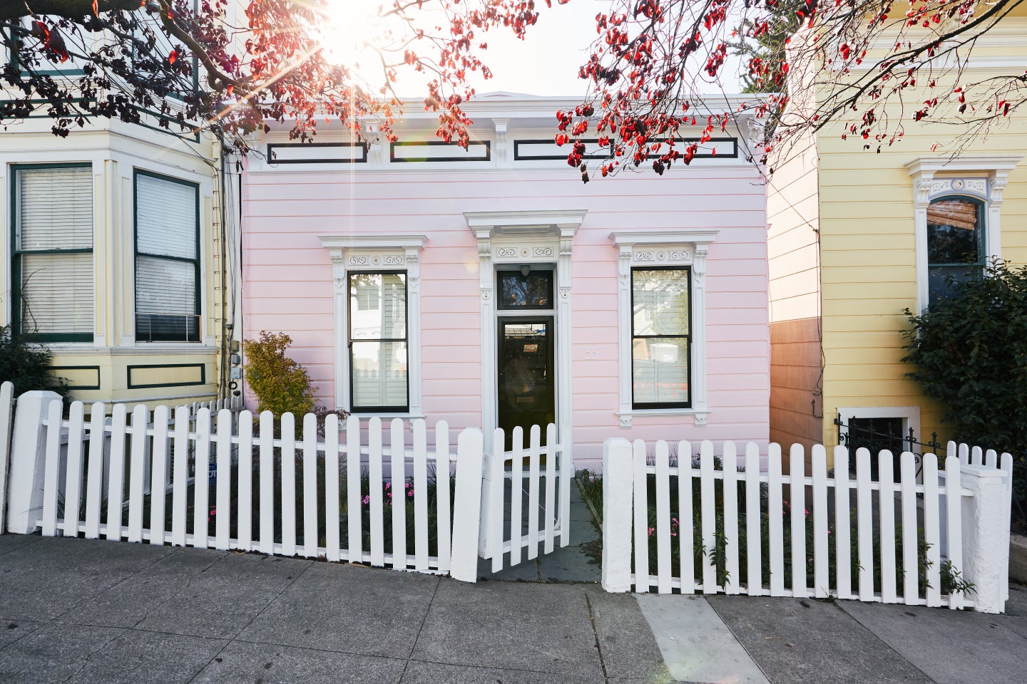 tiny pink house lined with white picket fence