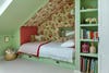 Girl's bedroom with pistachio-colored walls and bed nook with red floral fabric.