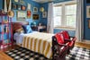 Boy's room painted blue with red vintage stadium seating at the foot of bed. 
