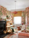 Little girl's room with pink botanical wallpaper and pink pendant lamp. 