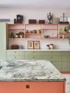 Sage green kitchen cabinets with pink walls.
