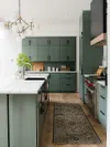 Kitchen with sage green cabinets and carpet on floor. 