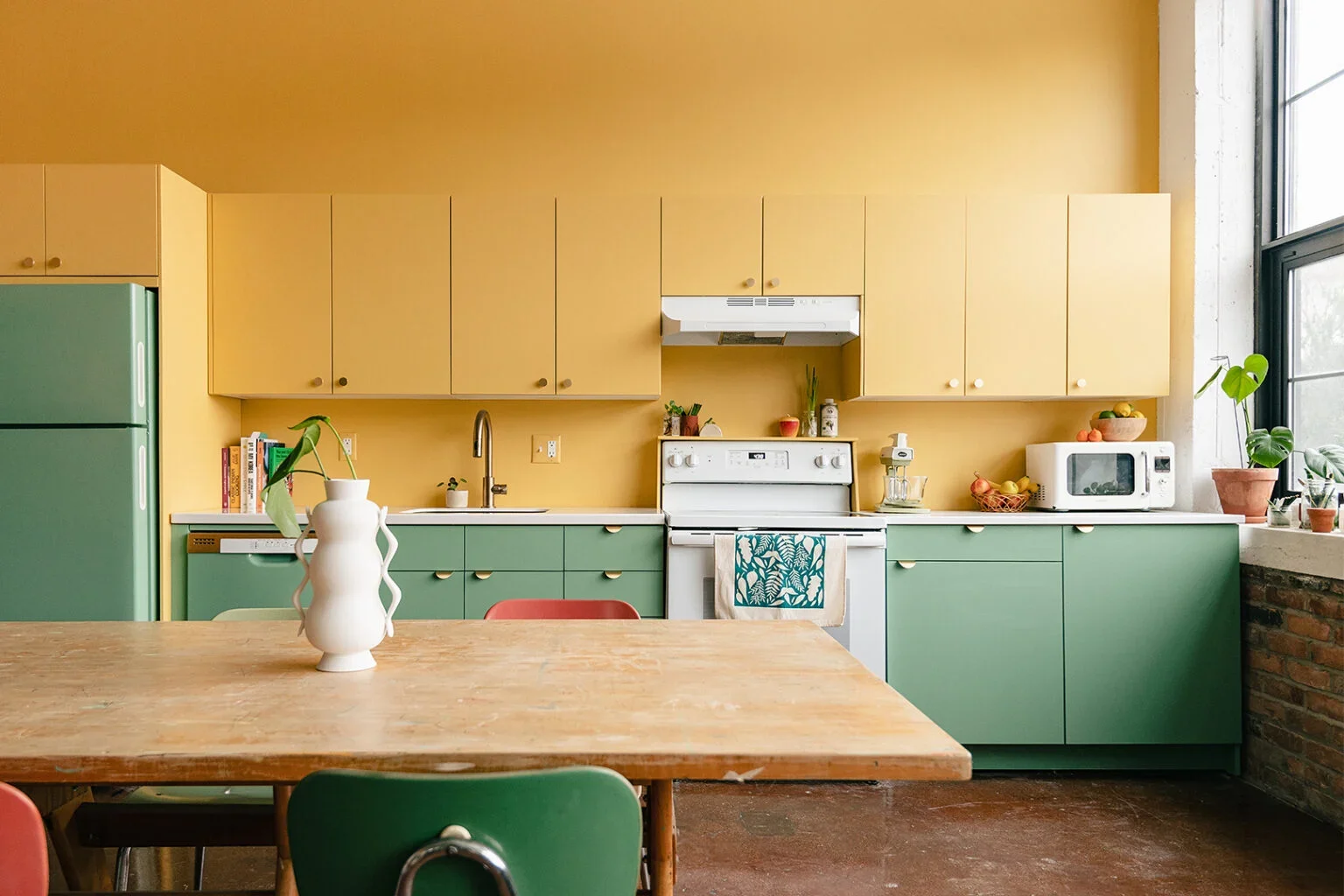Kitchen painted with yellow cabinets on top and sage green cabinets on the bottom.