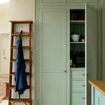 Wood ladder leaning on sage green kitchen cabinet doors.
