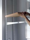 person putting on wood shelf