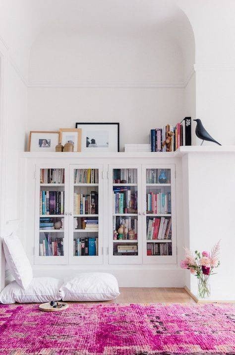 all white interiors white bookshelf with pink rug