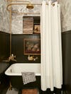 Clawfoot bathtub with oil paintings hanging above
