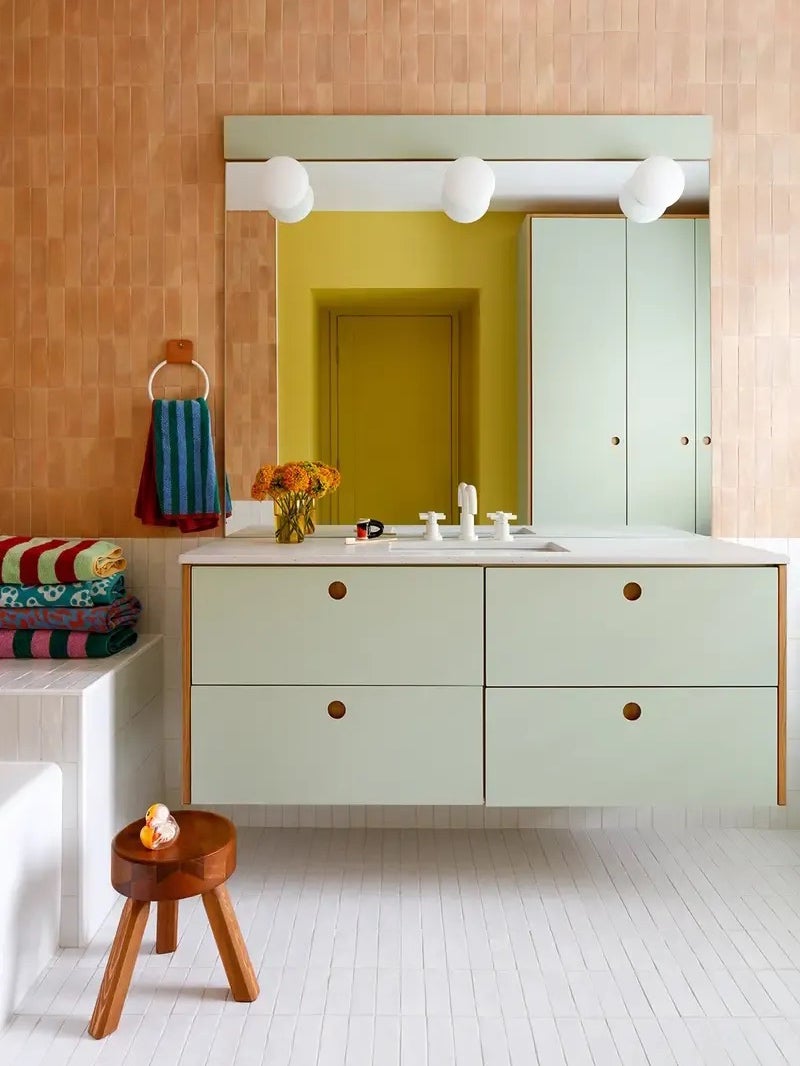 Bathroom with mint green cabinets and vivid striped towels