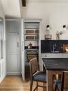 Light gray kitchen with hidden pantry door open to show extra storage