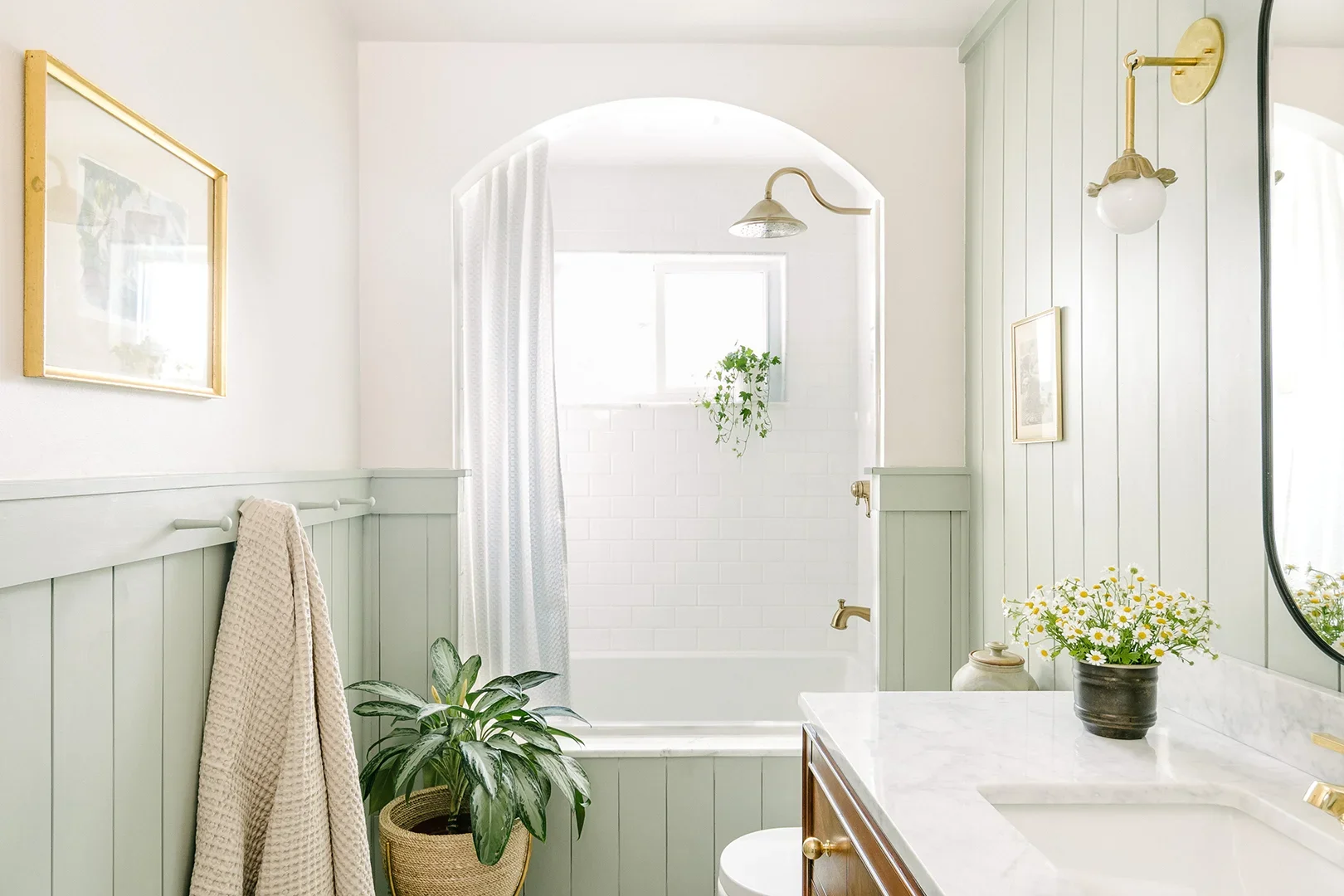 White and sage green bathroom with alcove shower. 