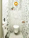 Small bathroom with green botanical wallpaper and green terrazzo floors.