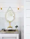 All-white bathroom with antique mirror and brass faucet.