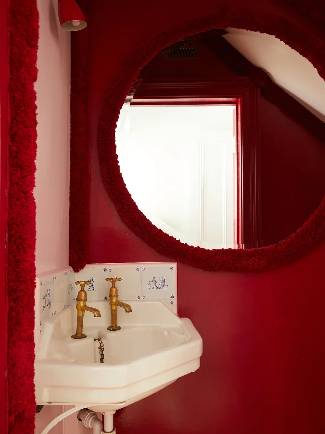 All-crimson red powder room with round mirror.