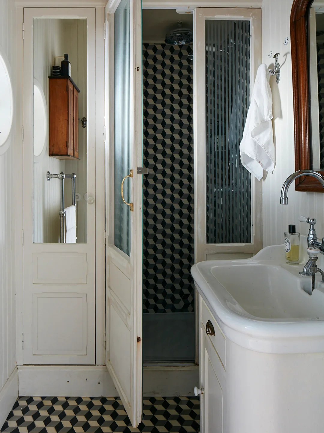 Small bathroom with black-and-white geometric tiled floor and shower.