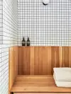 Bathroom with white square tile and cedar bench.