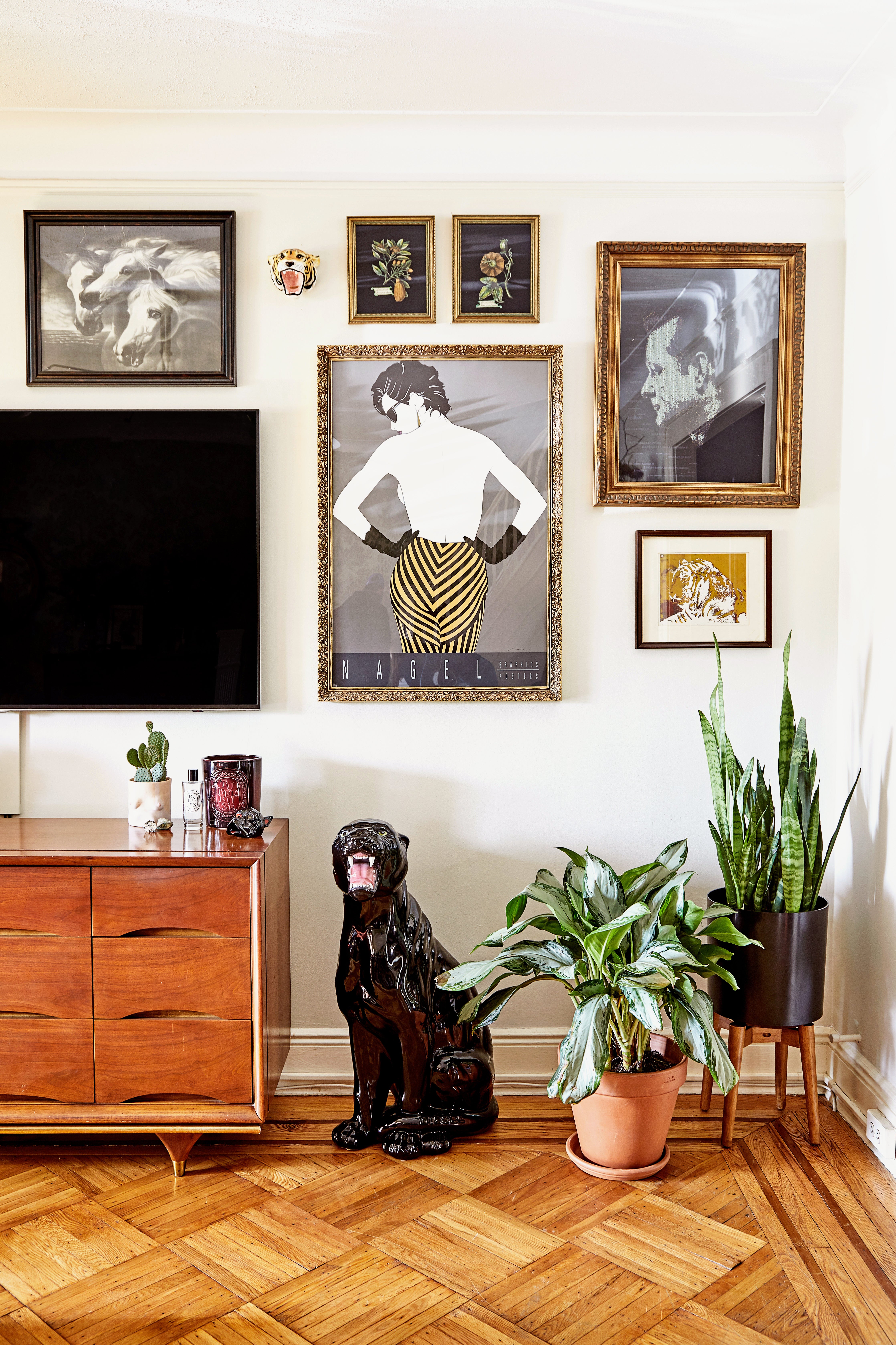 Corner of living room with white walls, graphic art prints, and plants