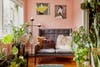 Pink room with Patrick Nagel prints, pink walls, gray sofa, and lots of plants