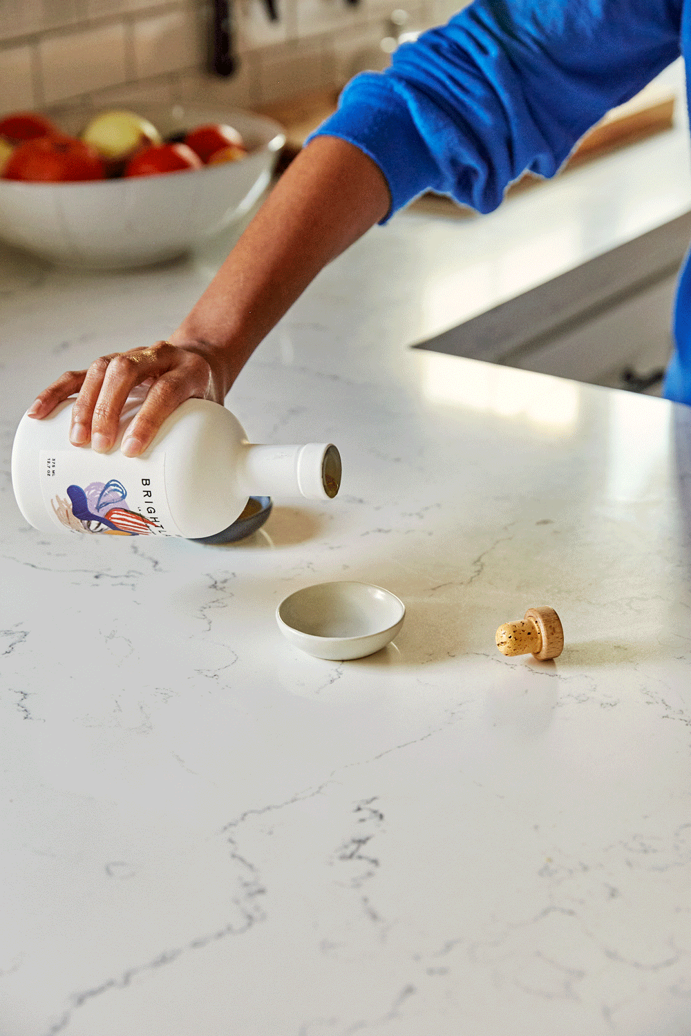 Hand pouring Brightland olive oil into small bowl