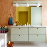 Bathroom with apricot-hued tiled wall and mint green floating vanity.