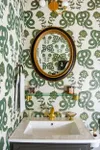 Bathroom with black oval mirror, and snake print wallpaper. 