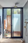 Blue plaster-style shower with black framed doors that open to outdoor shower. 