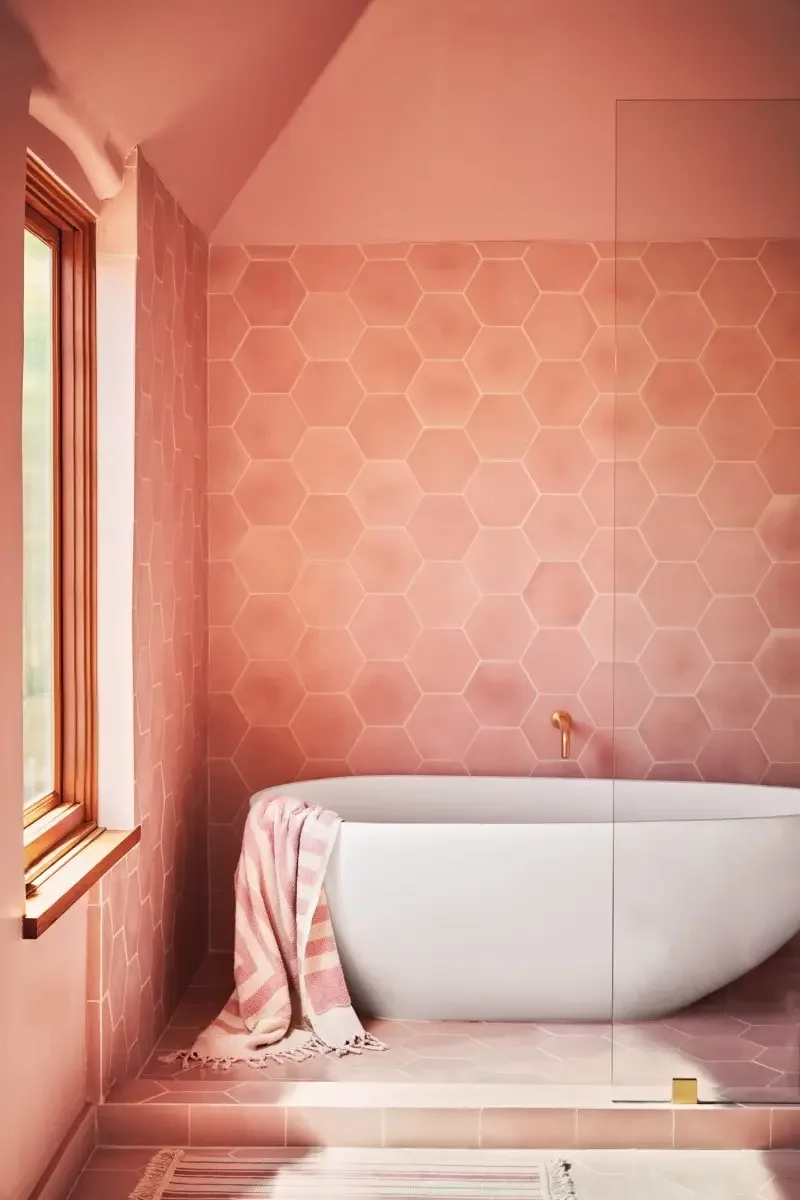 All-pink bathroom with white soaking tub on elevated floor. 