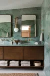 Bathroom with wood vanity and jade-colored stone lining walls.