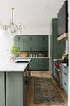 large kitchen with green cabinets and black hardware