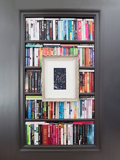 black bookcase with colorful spines and a frame in the middle