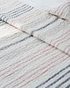 White quilt with pink and gray stripes.