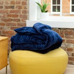 Yellow pouf with blue blanket.