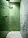 curved shower with long narrow green tiles