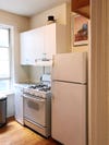 small kitchen with white fridge, oven, and cabinets