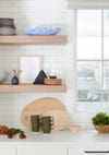 close up shot of floating wood shelves topped with colorful dishes and wood cutting boards