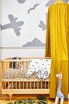 nursery crib with gray plane and mountain painted on the wall