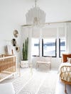 wide shot of zen, white nursery with a crib and bed 