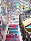colorful, maximalist staircase with pink and blue runner and paisely pattern wallpaper