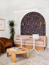 pink sofa elevated on wood block with a bold wallpaper arch behind it