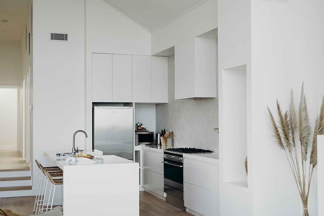 White kitchen with stainless steel fridge. 