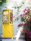 bright yellow dutch door surrounded by pink flowers