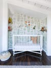 sloped white ceiling over a wallpapered nook wiht a crib in it